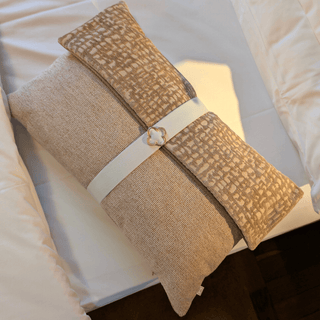 Roze sierkussen met witte band ligt op bed