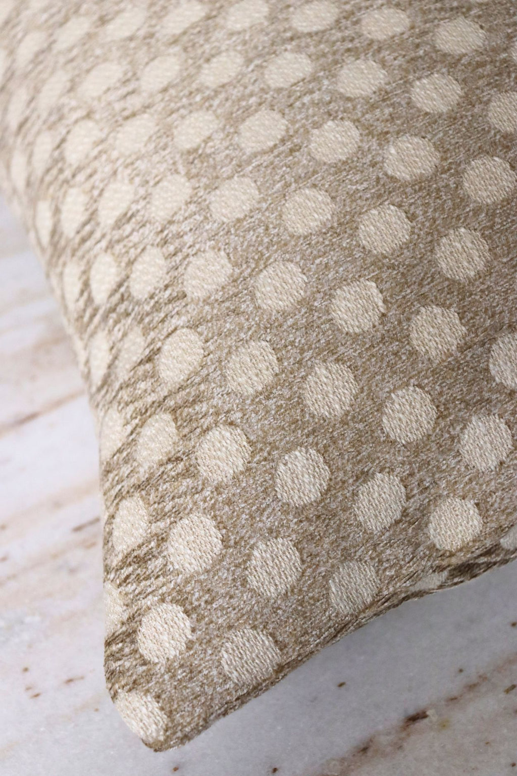 De stof van een goudbeige sierkussen met stippen.