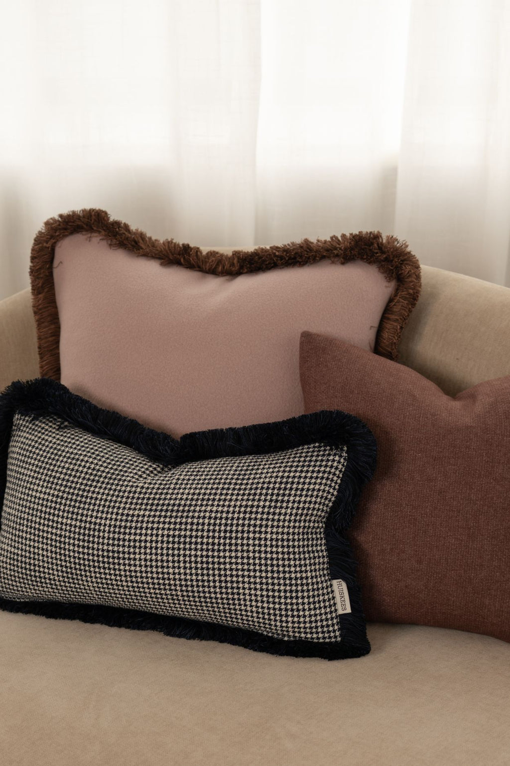 Er liggen drie kussens op ee  beige bank.