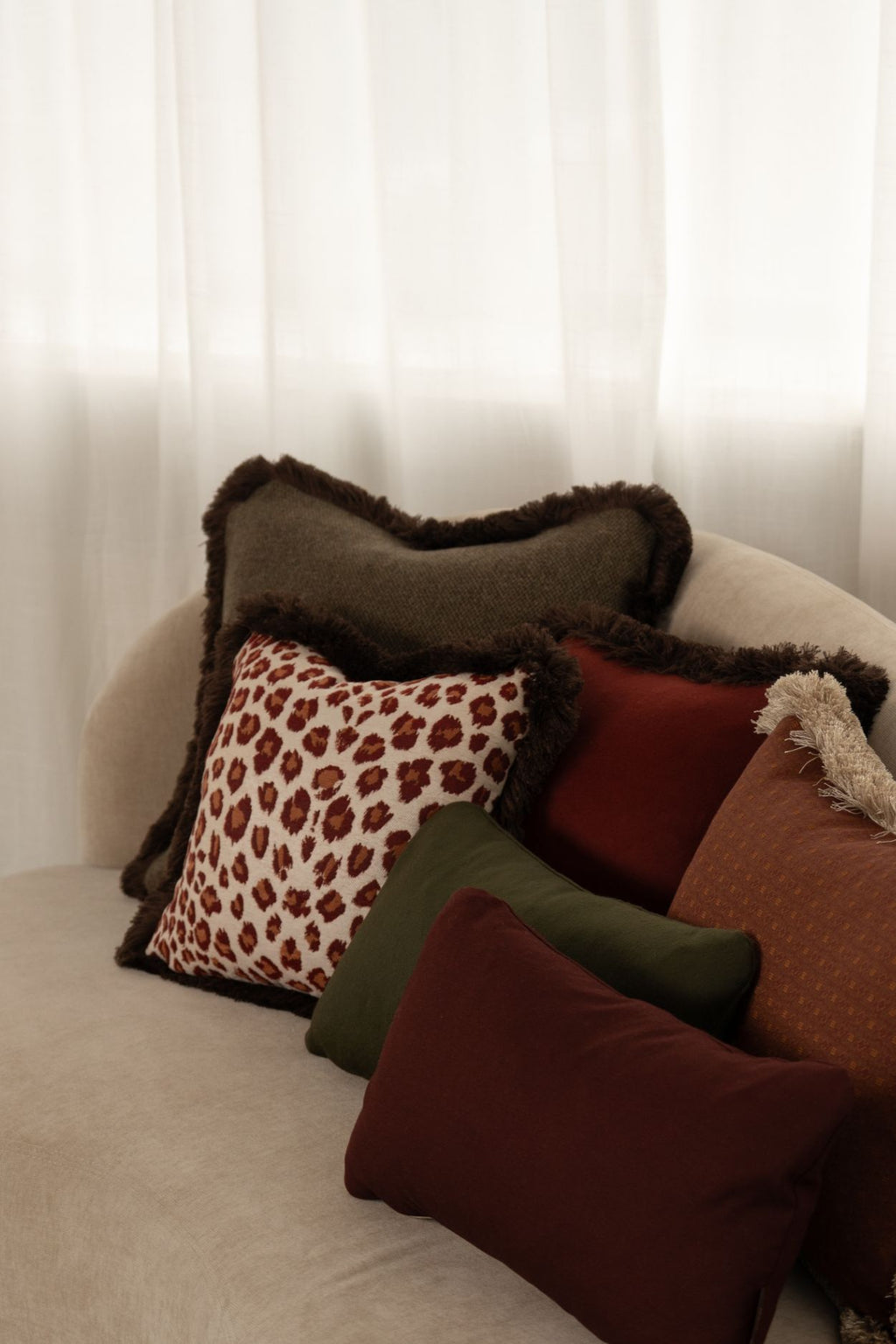 Groene, rode en oranje kussens liggen op een bank.