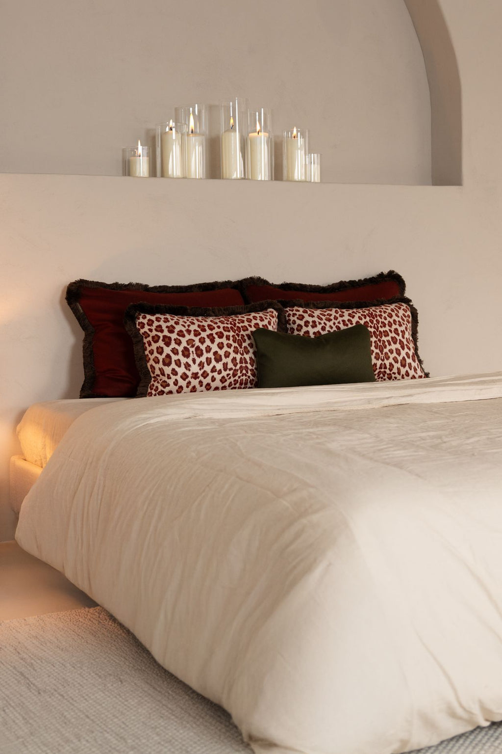 Rode en groene sierkussens in grote formaten liggen op bed.