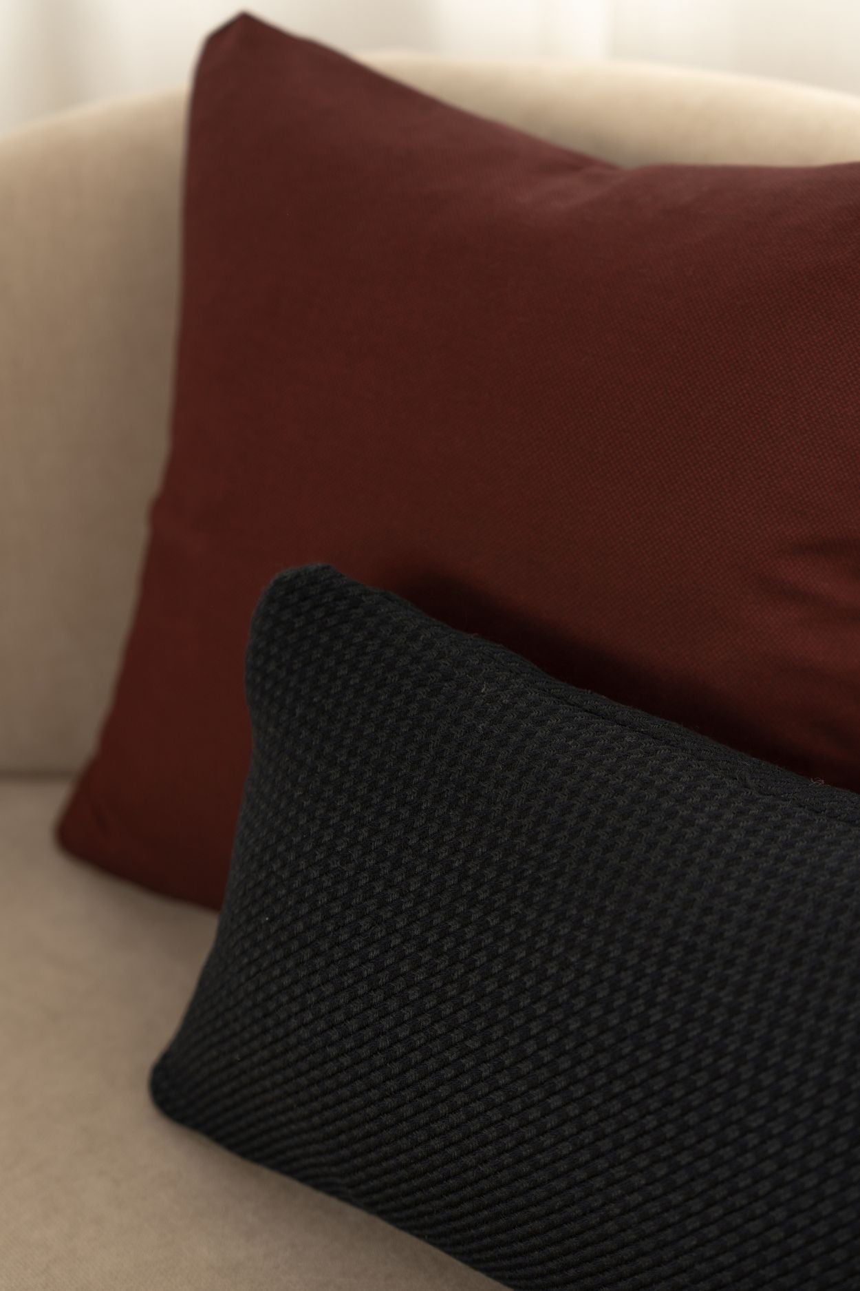 Een rood en donkerblauw sierkussen liggen op een beige bank.