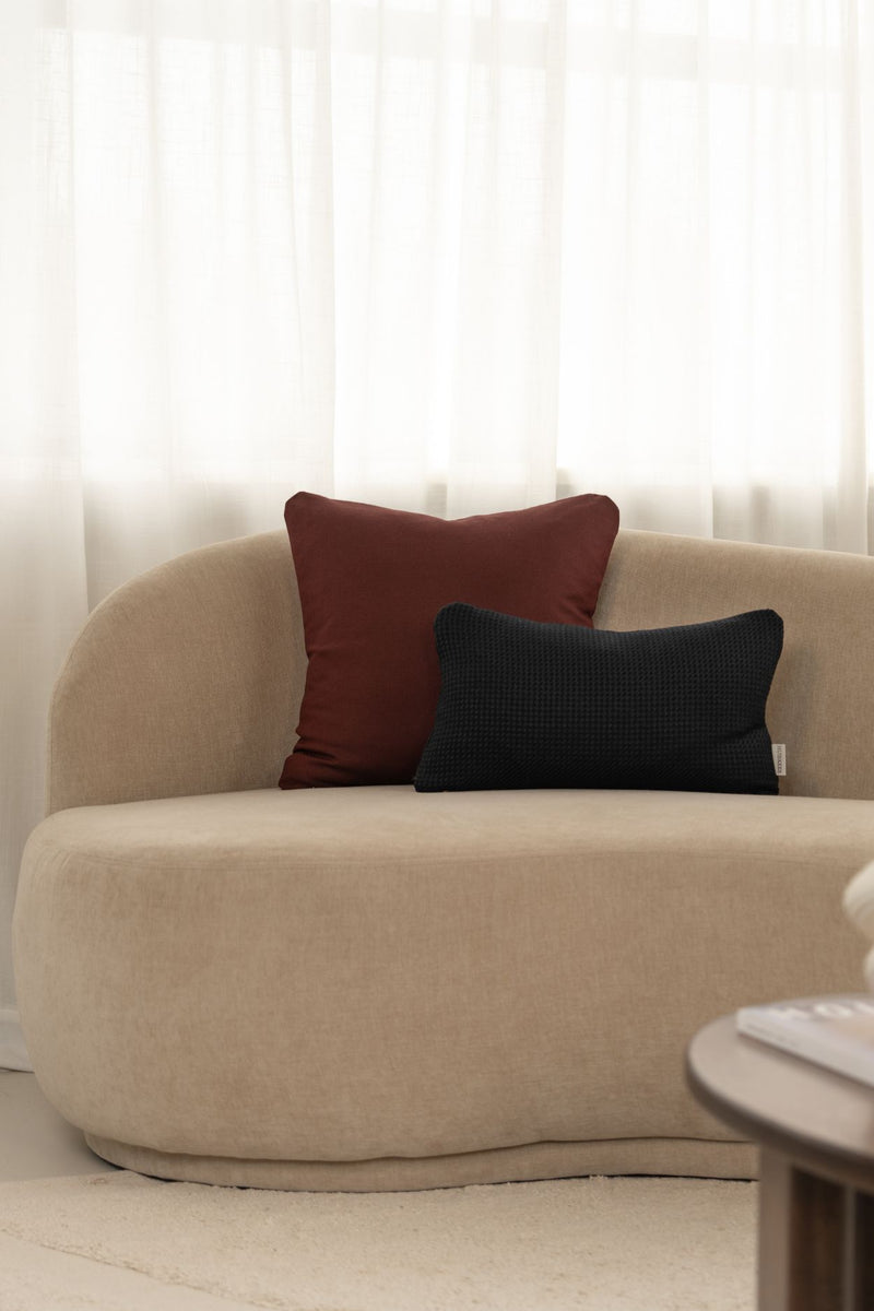 Luxe rood en donkerblauw sierkussen liggen op een beige bank.