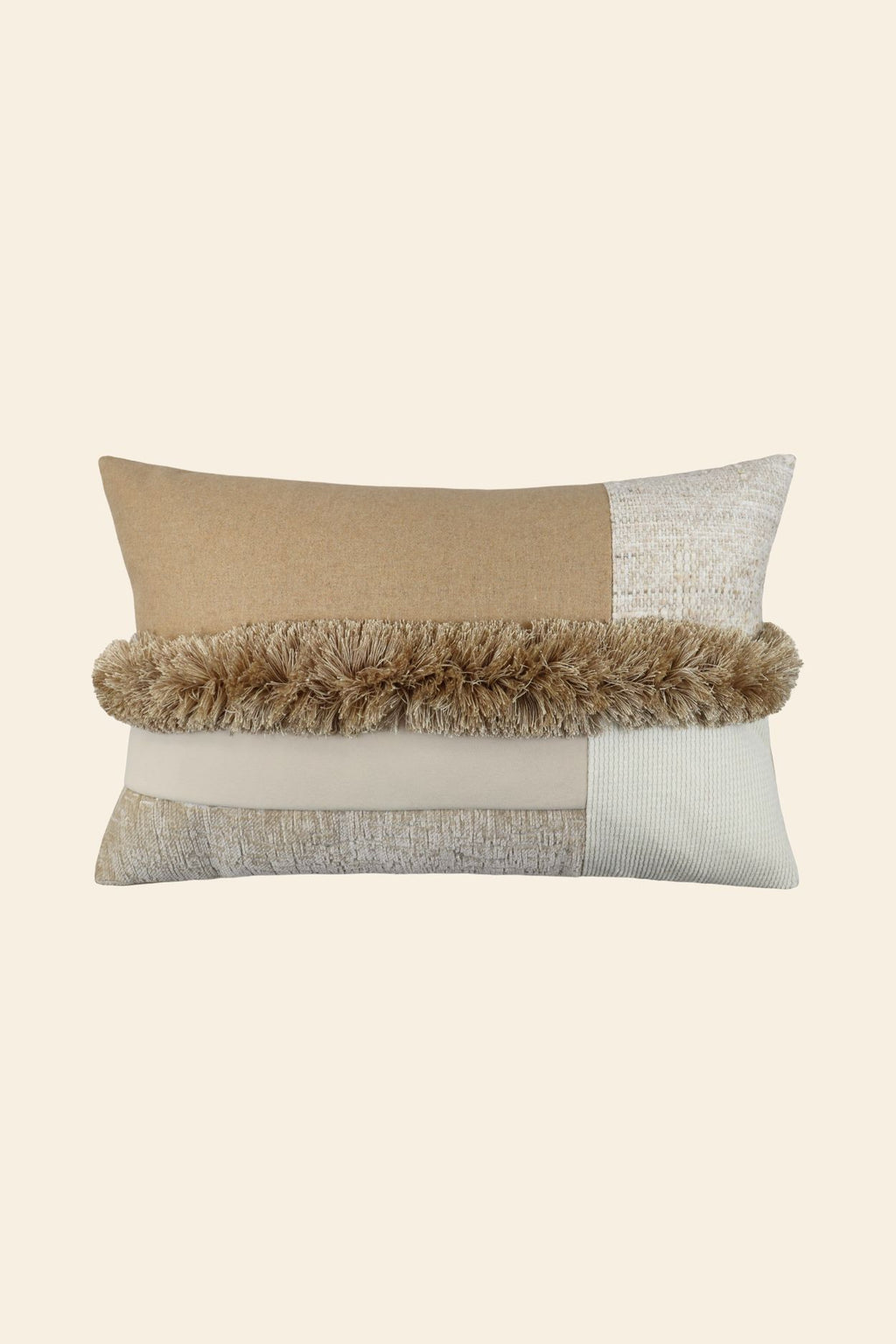 De voorkant van een beige sierkussen met verschillende stoffen en franjes in het midden.