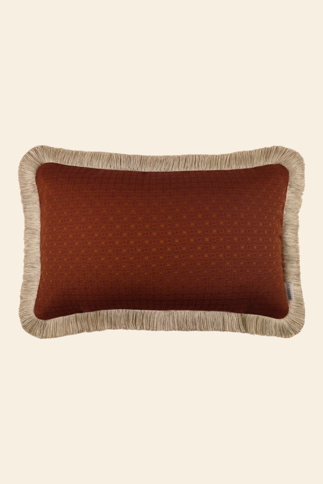 Oranje sierkussen met beige franjes in een rechthoekig formaat.