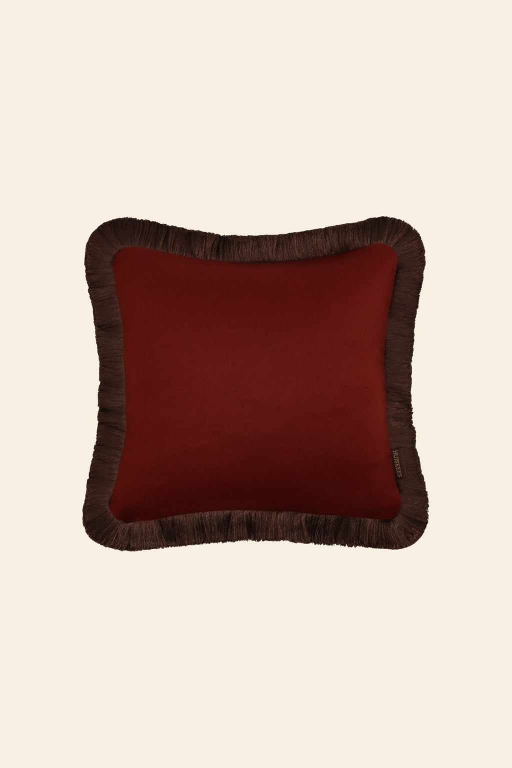 De voorkant van een donkerrood sierkussen in een vierkant formaat met donkerbruine franjes.