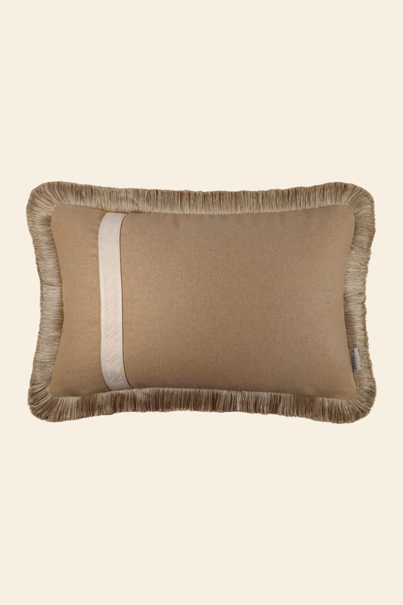 De voorkant van een wollen sierkussen met band en franjes.