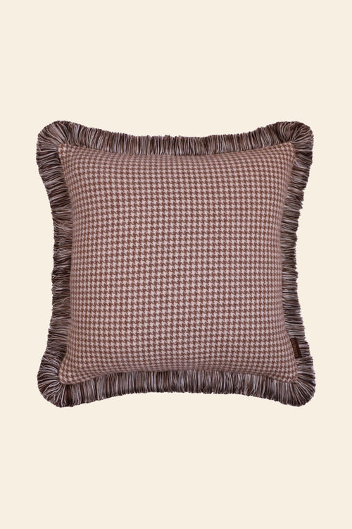 De voorkant van een beige sierkussen met pied de poule motief en franjes.