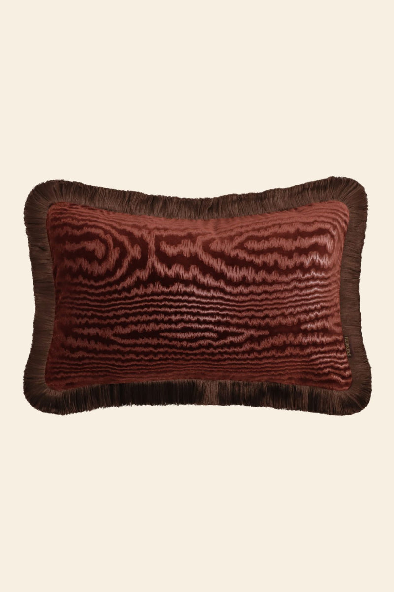 De voorkant van een roze velours kussen met franjes.