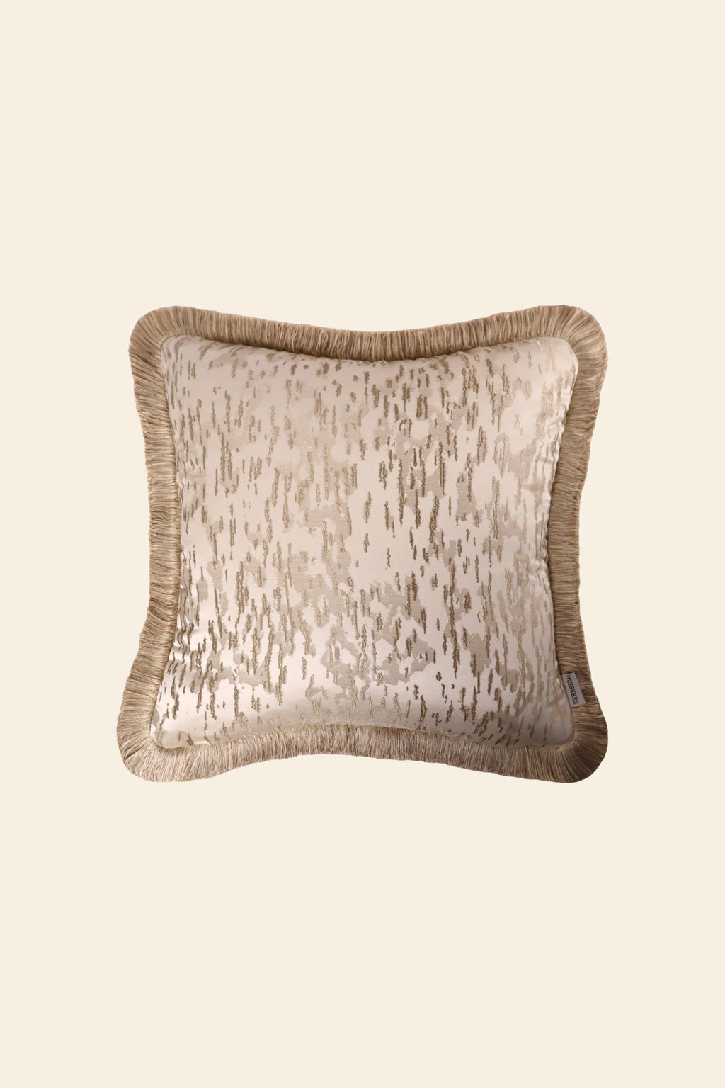 De voorkant van een luxe beige sierkussen met beige franjes.