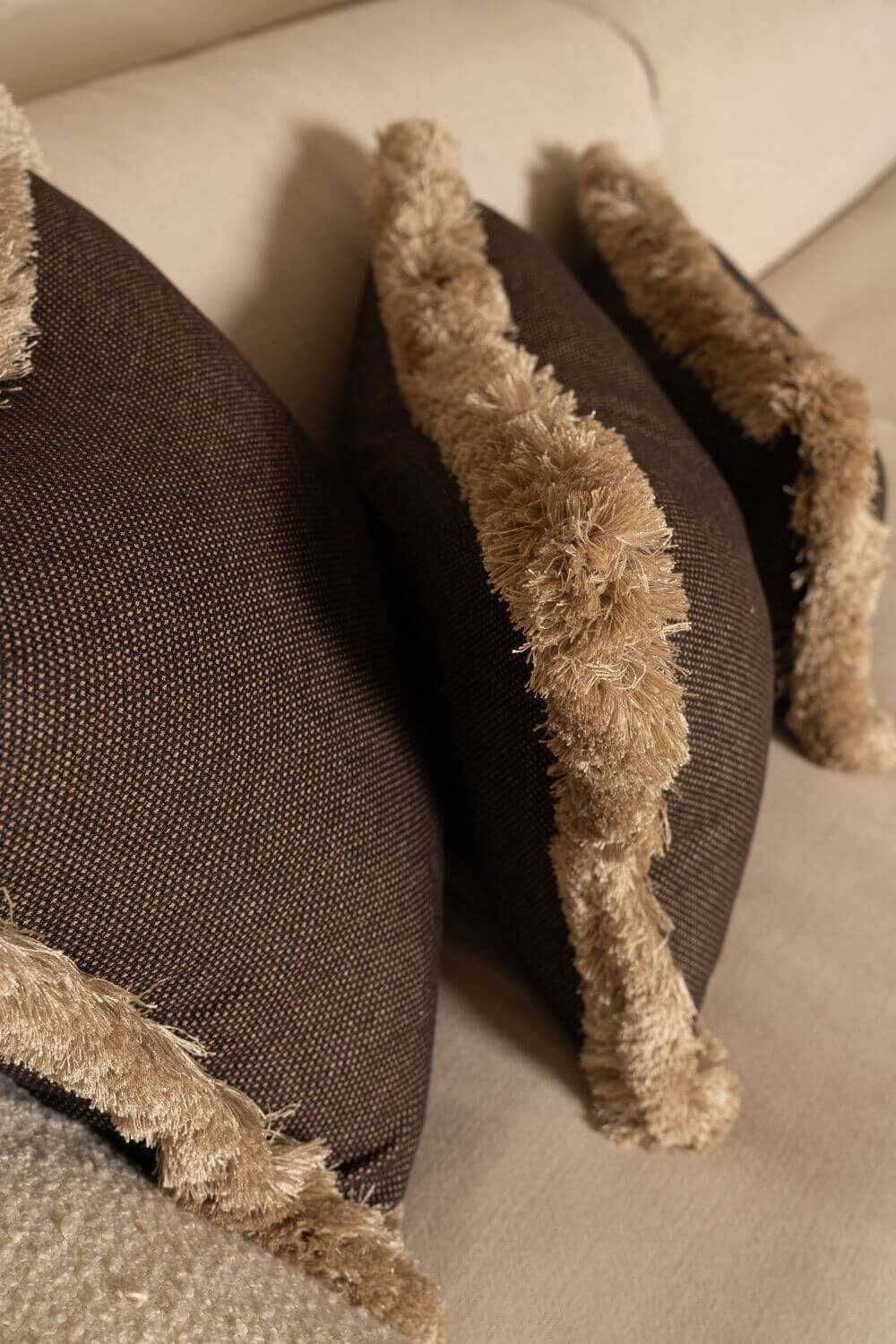 Een close up van bruine sierkussens met beige franjes
