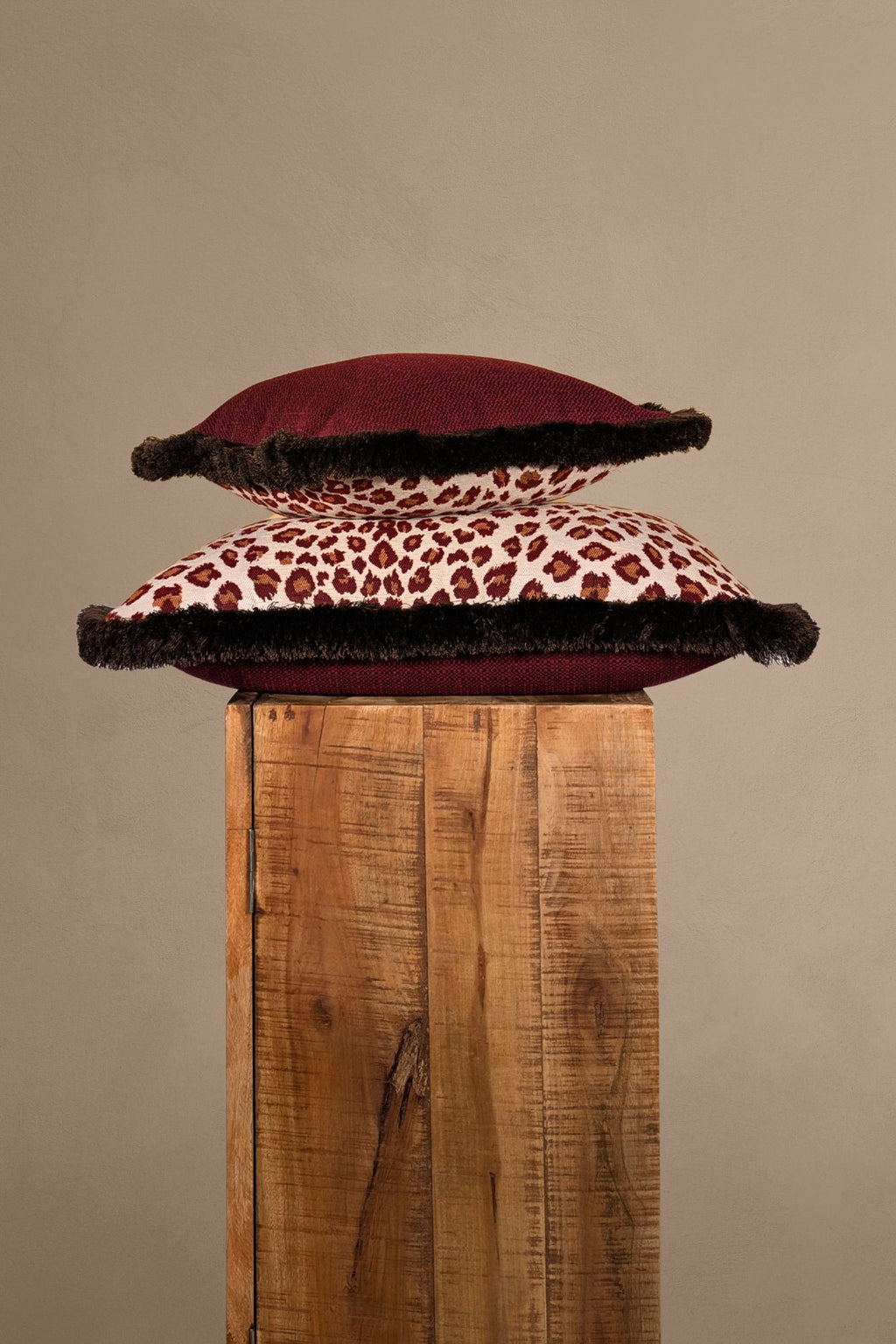 Twee rode sierkussens met luipaardmotief liggen op elkaar.