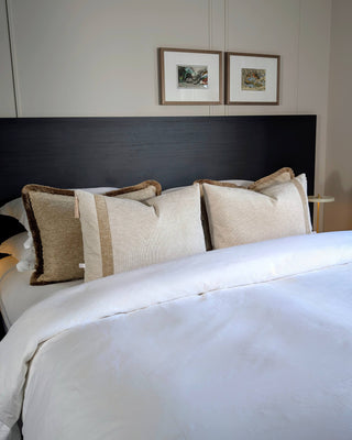 Beige sierkussens liggen op bed