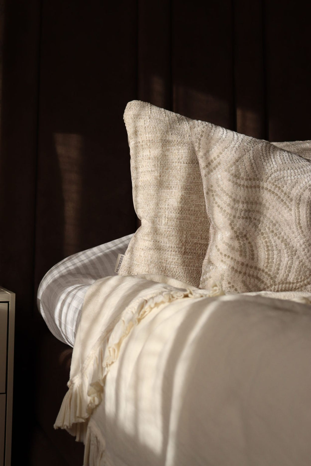 Crème witte sierkussens liggen op een opgemaakt bed.