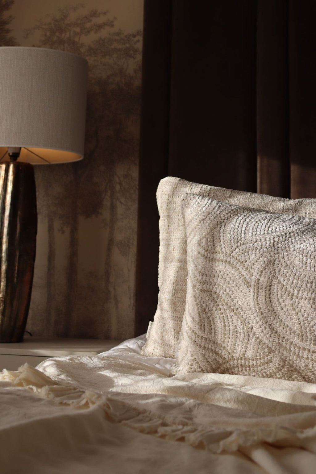 Crème witte sierkussens liggen op een luxe bed.