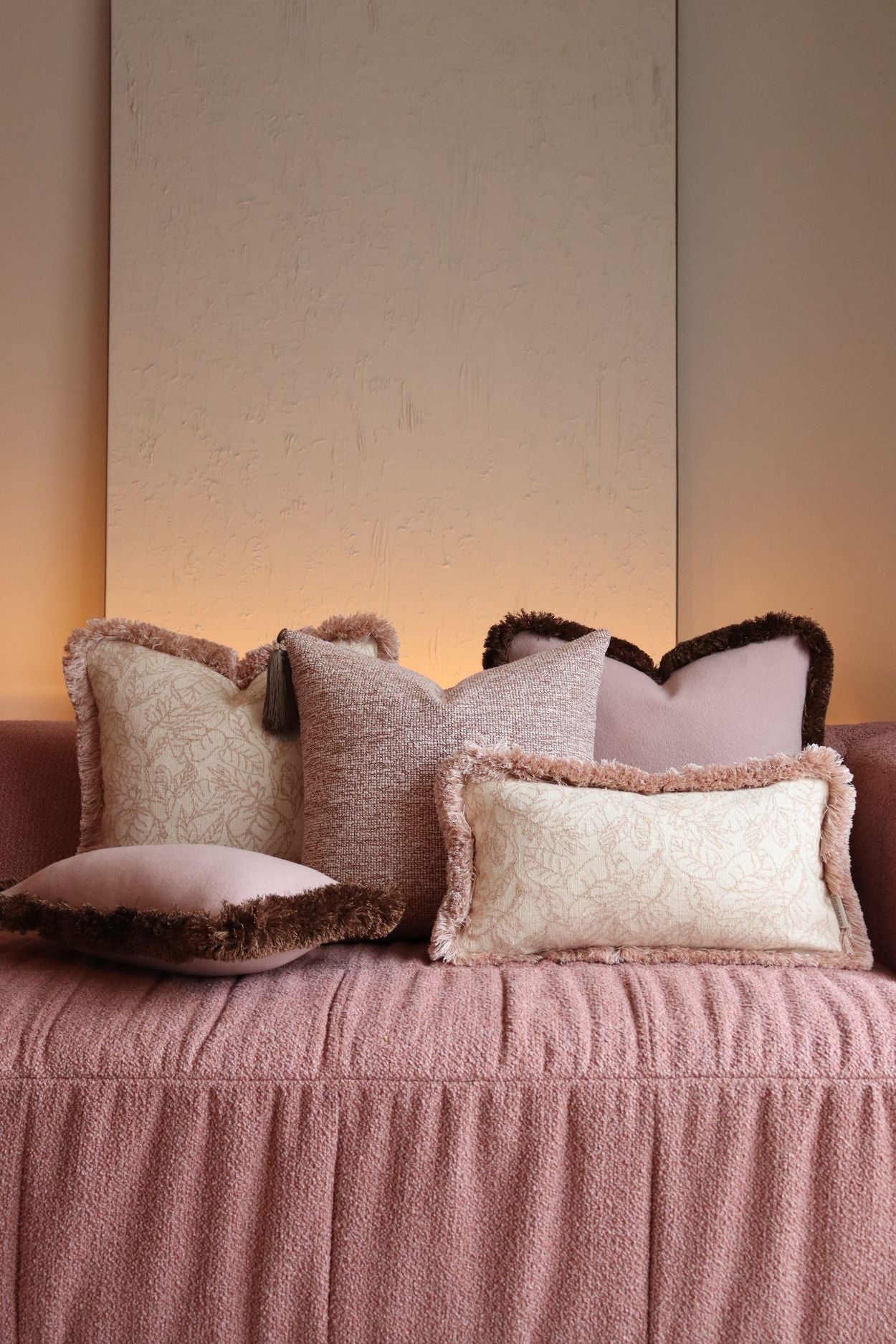 Luxe roze sierkussens met franjes en kwastjes liggen op een roze bank