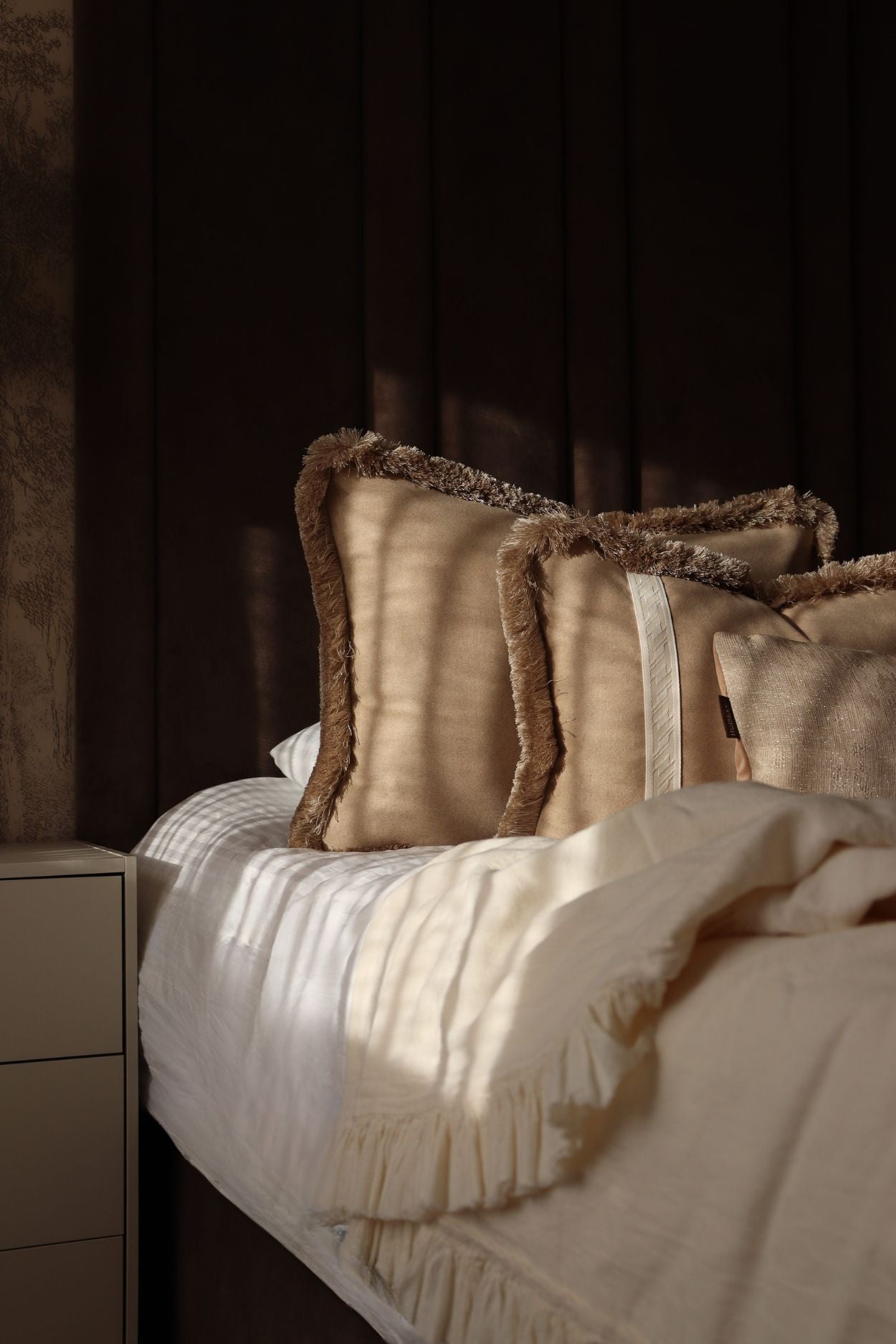 Luxe beige sierkussens in groot formaat en met beige franjes voor op bed.