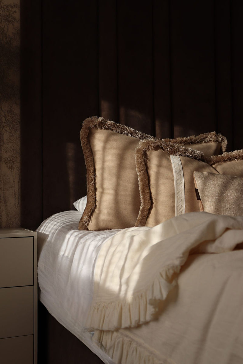 Luxe beige sierkussens in groot formaat en met beige franjes voor op bed.