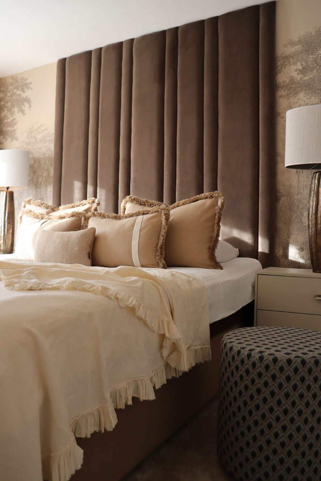 Een luxe hotel chique slaapkamer met grote beige sierkussens op bed.