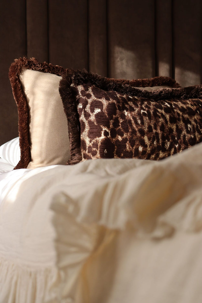 Grote sierkussens in het beige en bruin met franjes liggen op een luxe bed.