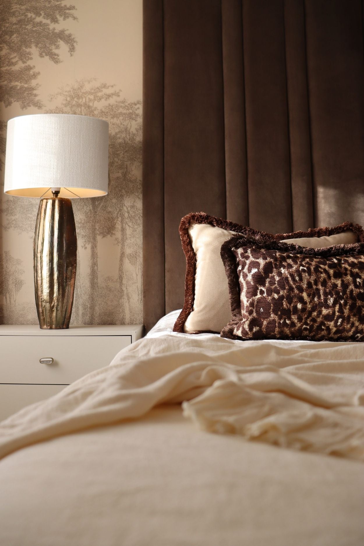 Een luxe slaapkamer in bruintinten met sierkussen in grote afmetingen die speciaal gemaakt zijn voor op bed.