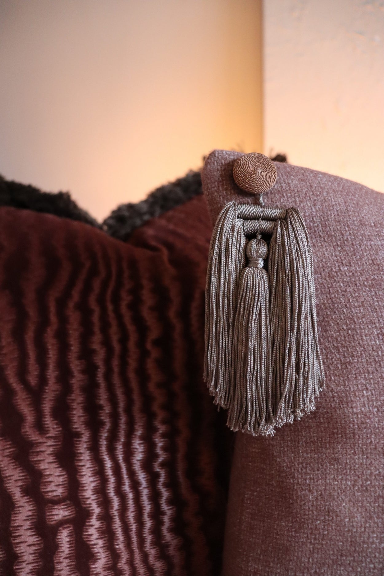 Een close-up afbeelding van een kwastje aan een roze sierkussen.