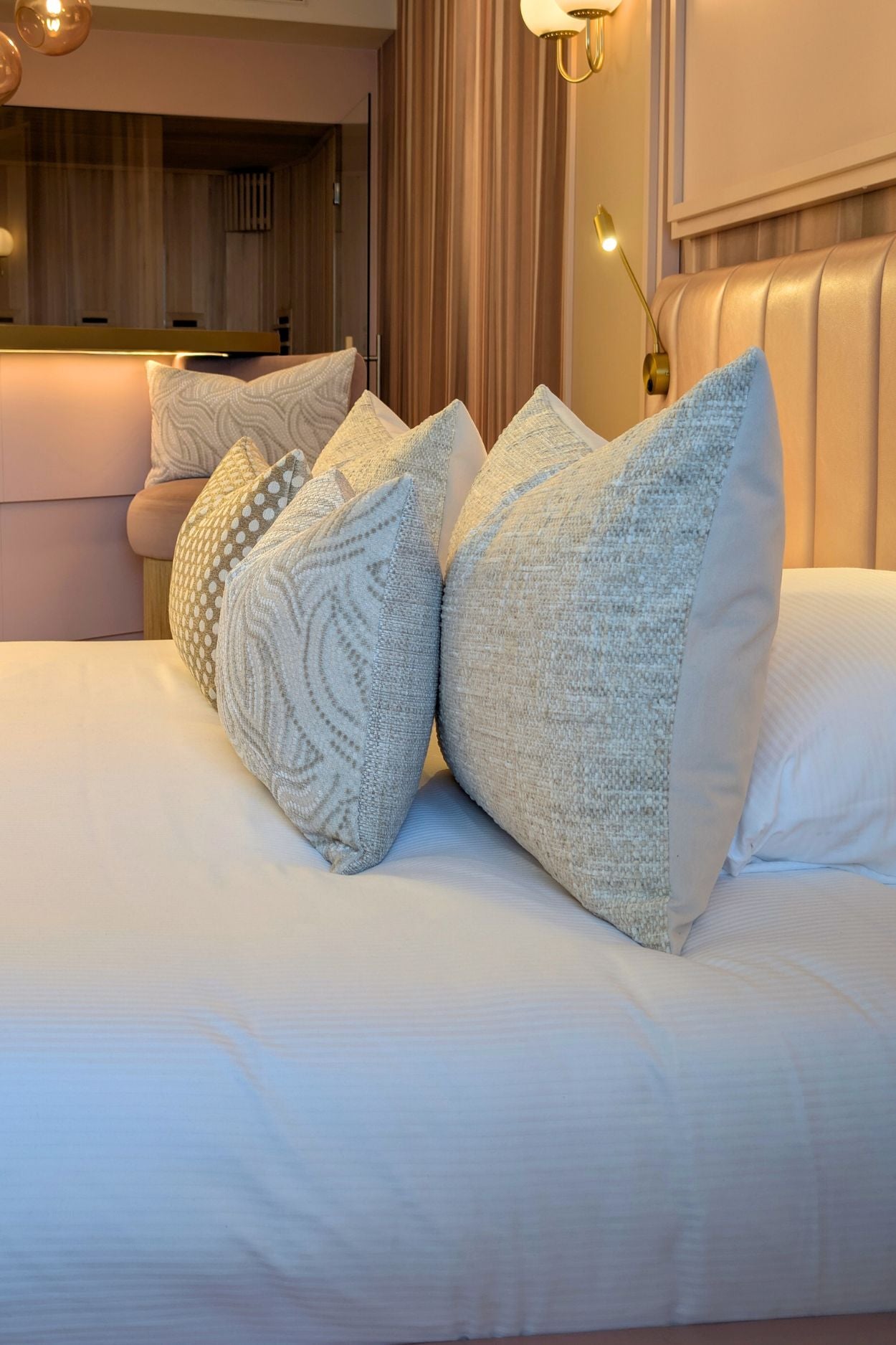 Crème witte sierkussens liggen op bed.